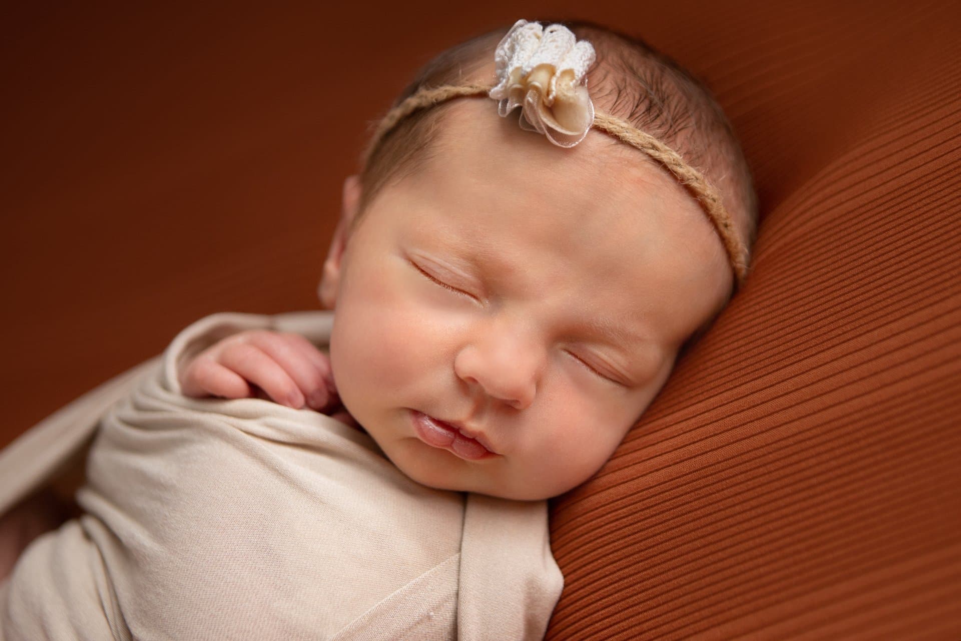 Newborn baby sleeping peacefully in a soft wrap during a professional photography session in Sheffield