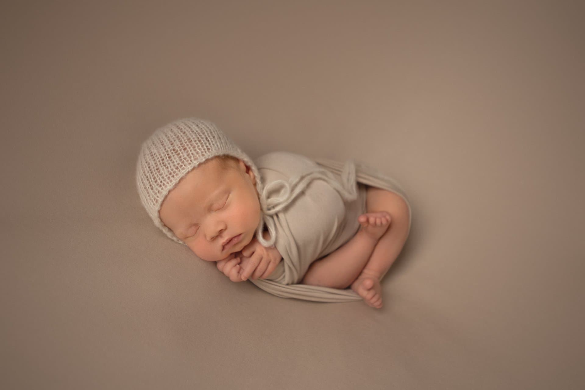 Photographer safely supporting a newborn baby during a posed photography session