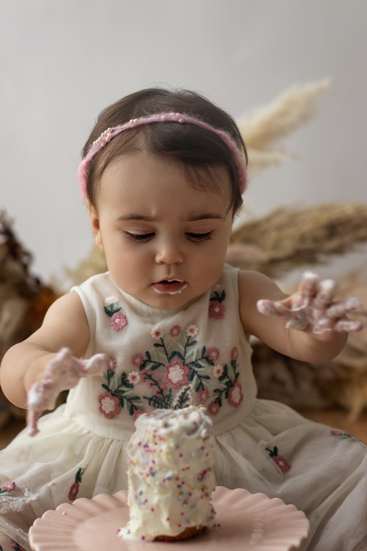 Baby gleefully smashing into a birthday cake covered in buttercream