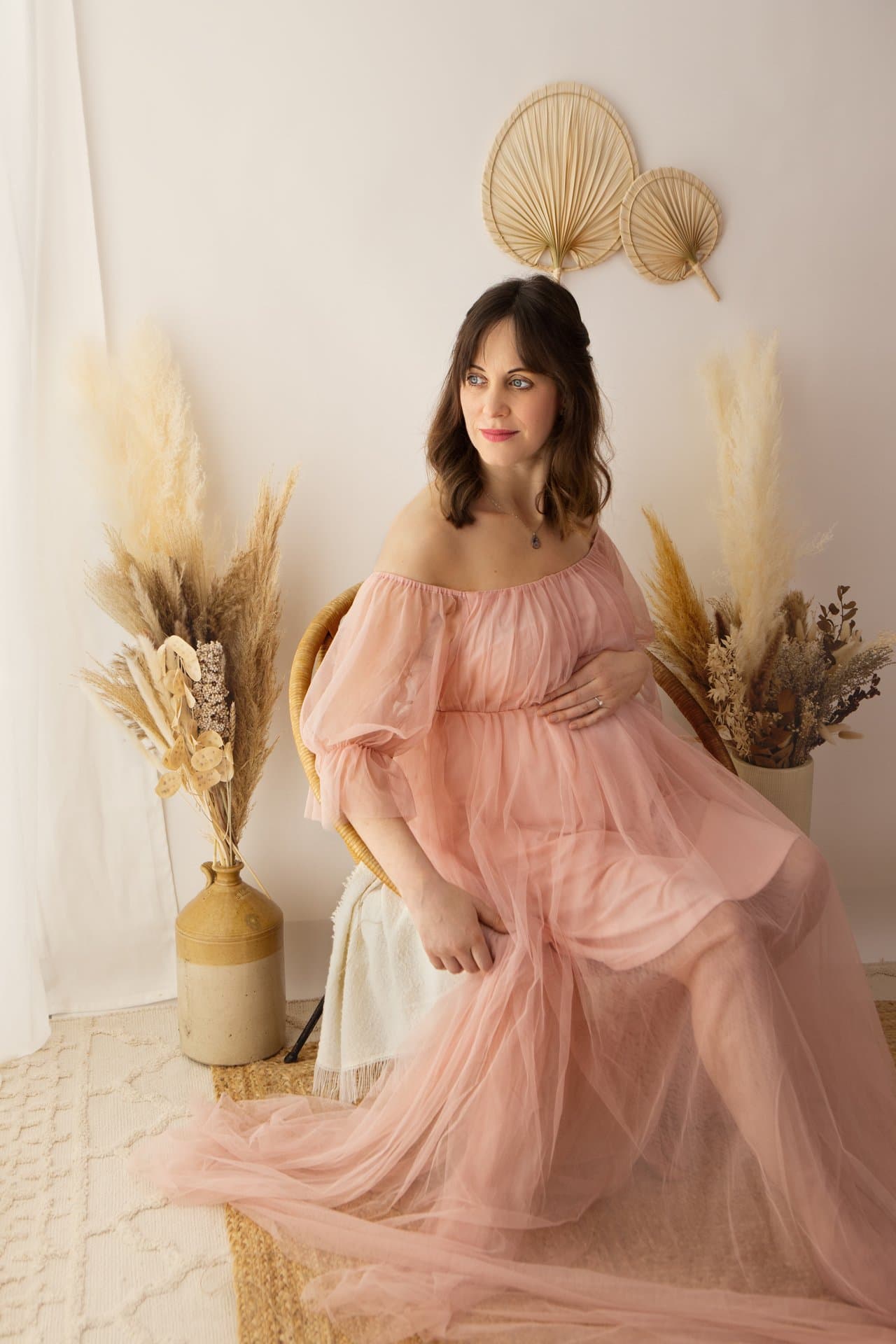 Pregnant woman in a flowing gown cradling her bump during a maternity photography session in Sheffield